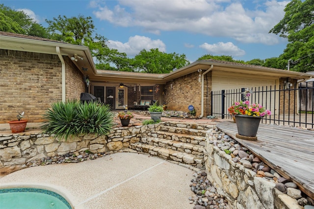rear view of house with a ceiling fan, a garage, brick siding, fence, and a patio