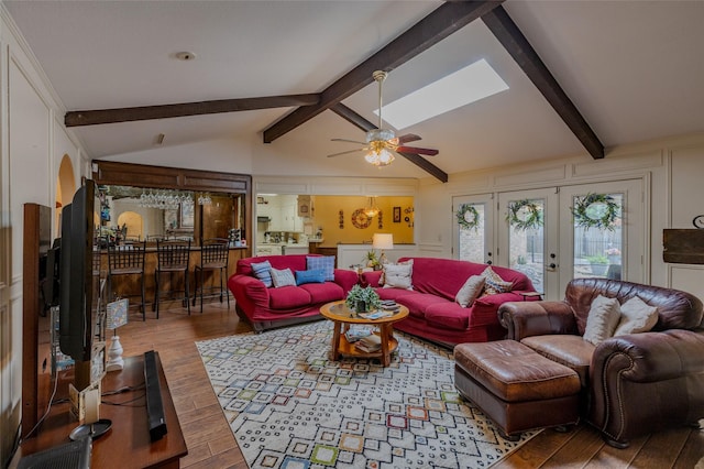 living area featuring vaulted ceiling with beams, a ceiling fan, wood finished floors, and french doors