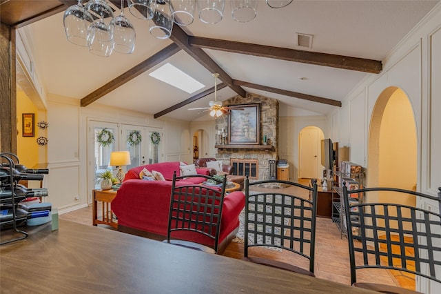 living area featuring arched walkways, lofted ceiling with beams, ceiling fan with notable chandelier, and wood finished floors