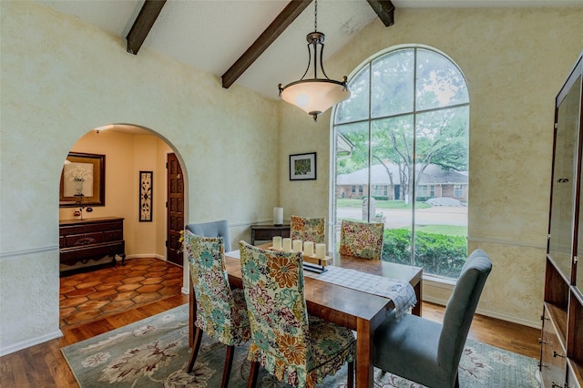 dining room with arched walkways, beamed ceiling, plenty of natural light, and high vaulted ceiling