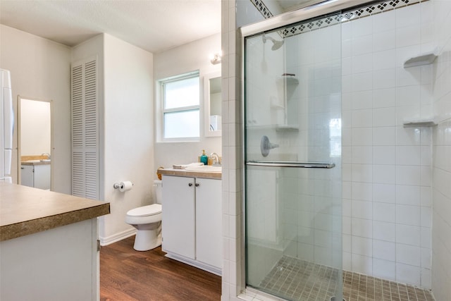 bathroom with vanity, a closet, a stall shower, and wood finished floors
