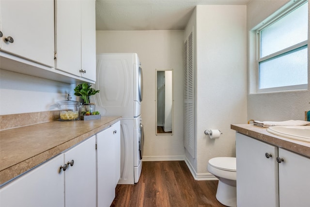 bathroom featuring vanity, stacked washer and dryer, wood finished floors, toilet, and baseboards