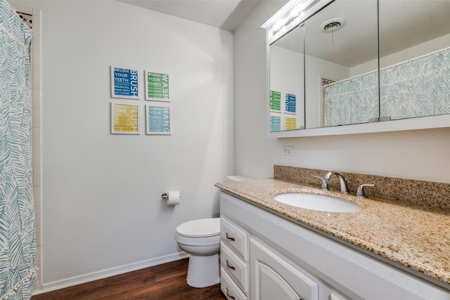 bathroom featuring vanity, toilet, baseboards, wood finished floors, and visible vents