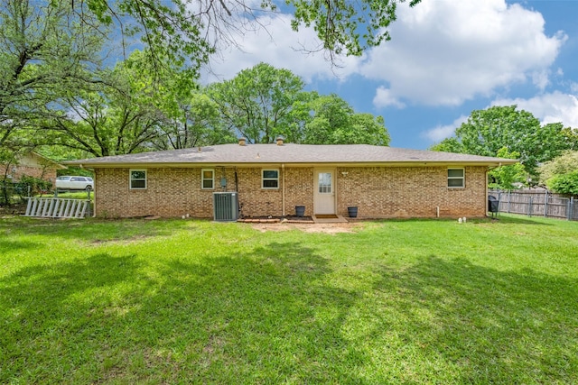 back of house featuring a yard, brick siding, central AC, and fence