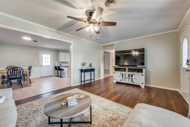 living room featuring visible vents, a textured ceiling, ceiling fan, and wood finished floors