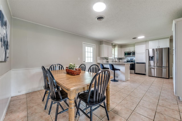dining area with crown molding, light tile patterned flooring, a textured ceiling, and visible vents