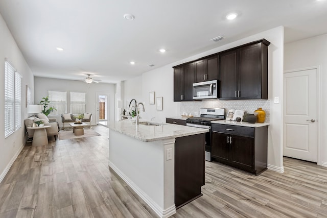 2021 Pine Stone Ln, Forney, TX 75126 - kitchen with visible vents, light stone counters, a sink, light wood-style flooring, and appliances with stainless steel finishes