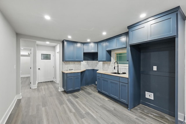 217 N Hawkins St, Waxahachie, TX 75165 - kitchen featuring baseboards, decorative backsplash, a sink, and light wood-style floors