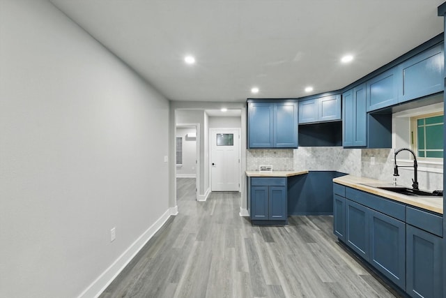 217 N Hawkins St, Waxahachie, TX 75165 - kitchen with backsplash, blue cabinetry, baseboards, recessed lighting, and light wood-style flooring