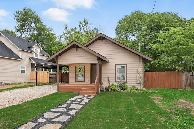 217 N Hawkins St, Waxahachie, TX 75165 - bungalow-style home featuring fence, covered porch, gravel driveway, and a front lawn