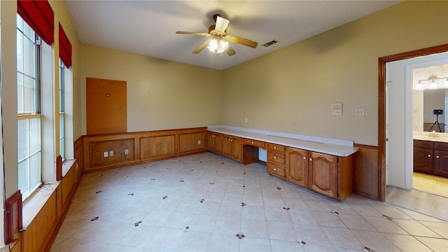unfurnished office featuring ceiling fan, visible vents, wainscoting, and a sink