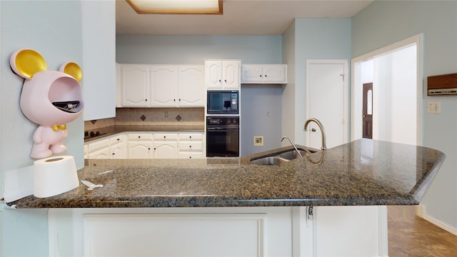 kitchen with white cabinets, a sink, a peninsula, backsplash, and black appliances