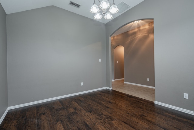 spare room with visible vents, arched walkways, wood finished floors, lofted ceiling, and an inviting chandelier