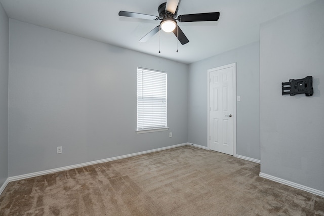 empty room featuring carpet floors, a ceiling fan, and baseboards