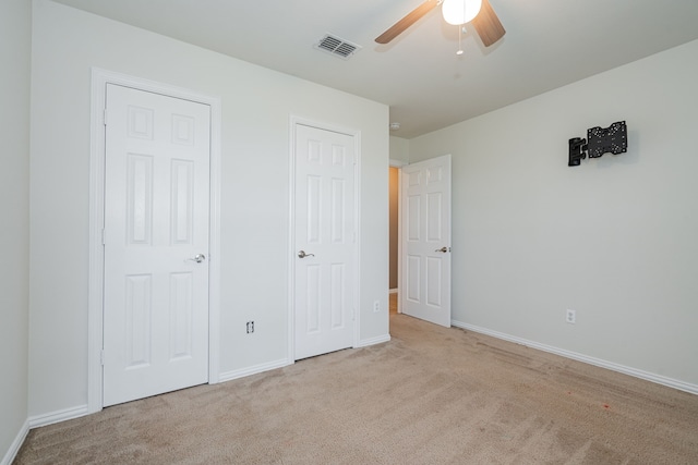 unfurnished bedroom featuring carpet floors, baseboards, ceiling fan, and visible vents