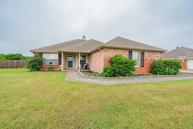 single story home featuring fence, a shingled roof, a front lawn, brick siding, and a chimney