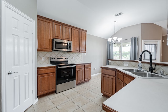 kitchen with brown cabinets, appliances with stainless steel finishes, a sink, decorative backsplash, and vaulted ceiling