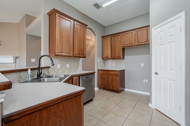kitchen with stainless steel dishwasher, brown cabinetry, visible vents, tasteful backsplash, and a sink