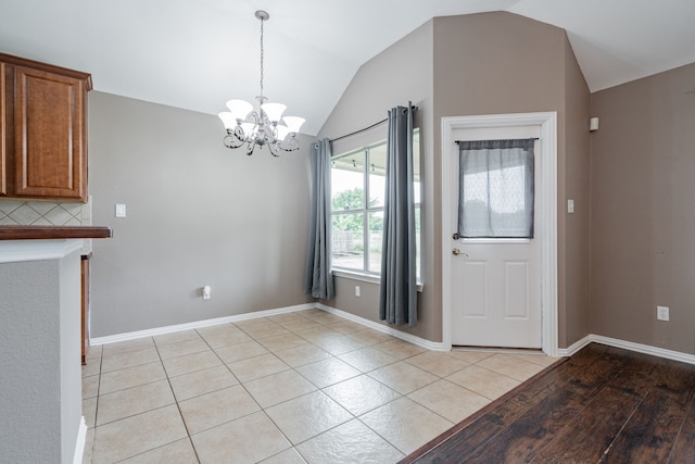unfurnished dining area with baseboards, light tile patterned flooring, lofted ceiling, and a notable chandelier