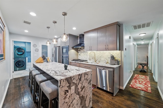 5243 Welden Ct, Fort Worth, TX 76132 - kitchen featuring visible vents, stacked washer / dryer, wall chimney exhaust hood, a sink, and appliances with stainless steel finishes