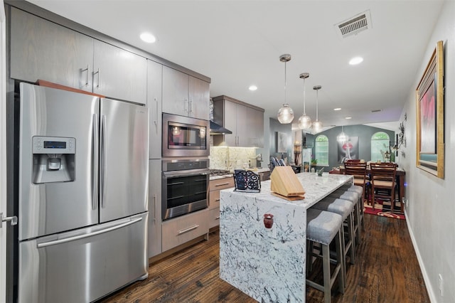 5243 Welden Ct, Fort Worth, TX 76132 - kitchen featuring visible vents, a breakfast bar, dark wood-type flooring, a center island, and appliances with stainless steel finishes
