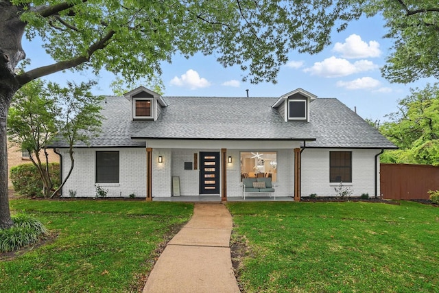 view of front of property featuring roof with shingles, brick siding, and covered porch