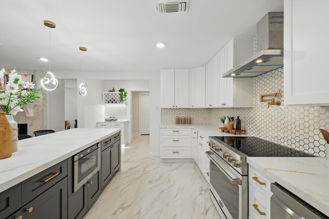 kitchen featuring stainless steel appliances, wall chimney range hood, white cabinets, and recessed lighting