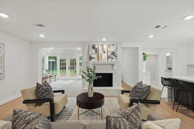 living area with wood finished floors, a high end fireplace, recessed lighting, baseboards, and french doors