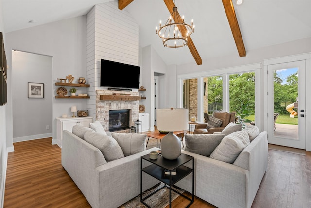 living room featuring high vaulted ceiling, a chandelier, a stone fireplace, and wood finished floors