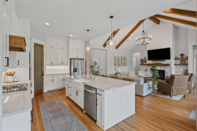 kitchen featuring white cabinets, appliances with stainless steel finishes, a sink, light wood-style floors, and backsplash