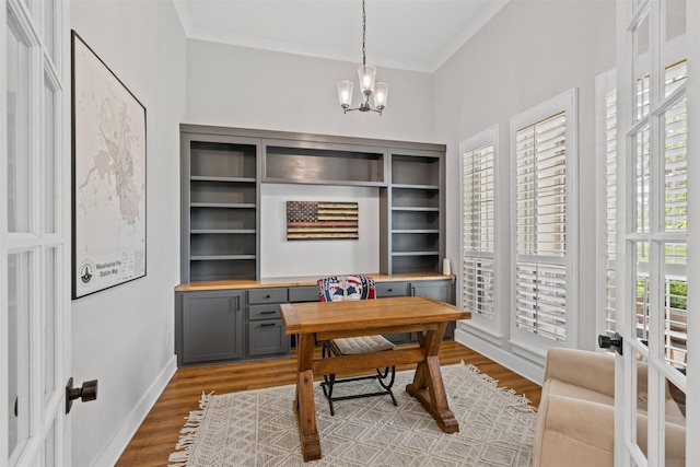 office area featuring baseboards, ornamental molding, wood finished floors, and a notable chandelier