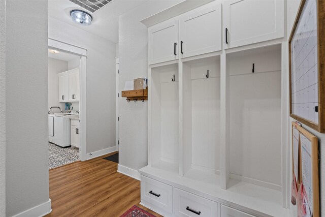 mudroom featuring baseboards, washer / dryer, and light wood-style flooring