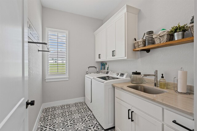 laundry area with baseboards, washing machine and clothes dryer, a sink, cabinet space, and light tile patterned floors