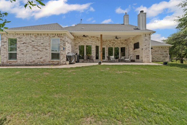 back of property featuring ceiling fan, a chimney, brick siding, a patio area, and a lawn