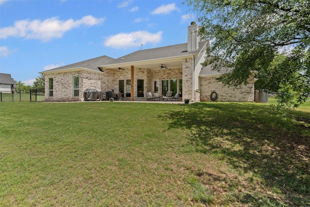 back of house with fence, brick siding, a ceiling fan, a patio area, and a yard