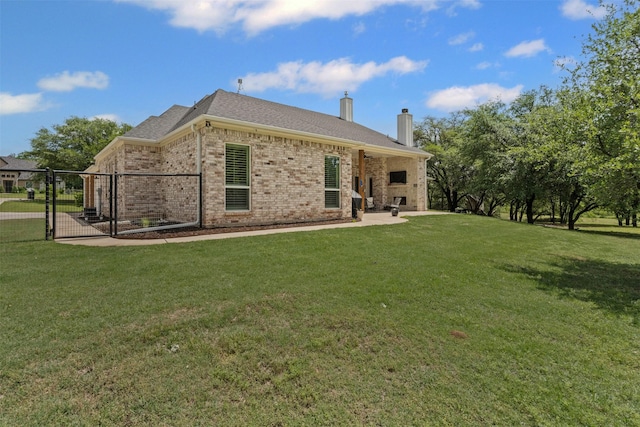 back of house with a patio, a chimney, brick siding, a gate, and a yard