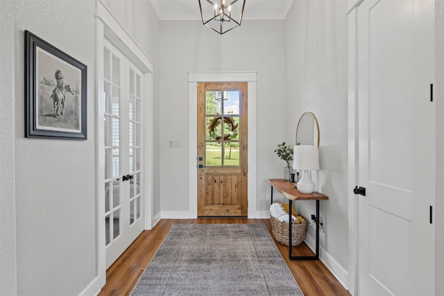 entryway with crown molding, dark wood-style flooring, baseboards, a chandelier, and french doors