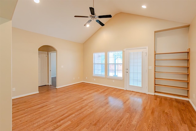 unfurnished room with a ceiling fan, arched walkways, baseboards, high vaulted ceiling, and light wood-style floors