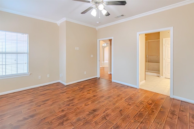 unfurnished room with a ceiling fan, visible vents, wood finished floors, baseboards, and ornamental molding