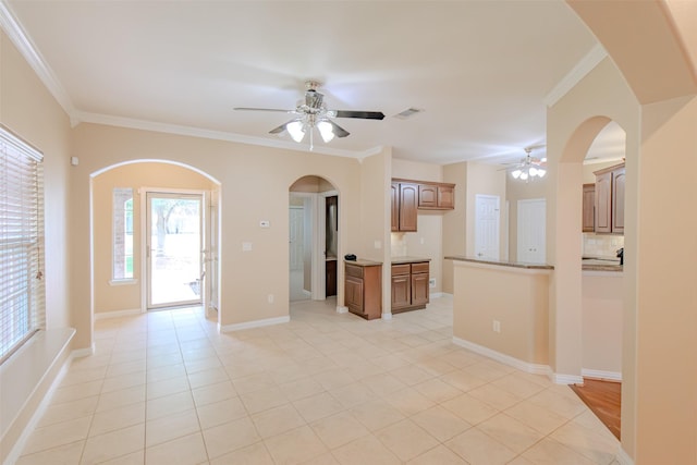unfurnished living room with visible vents, crown molding, arched walkways, a ceiling fan, and light tile patterned floors