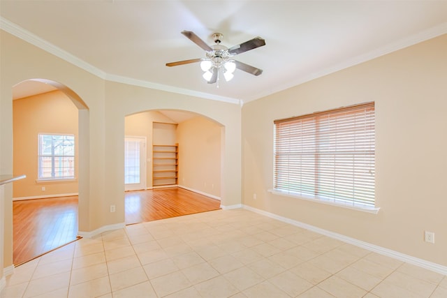 unfurnished room featuring crown molding, a ceiling fan, arched walkways, and baseboards