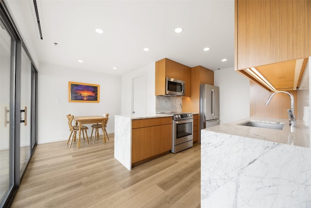 3831 Turtle Creek Blvd Unit 7E, Dallas, TX 75219 - kitchen featuring decorative backsplash, light stone countertops, light wood-type flooring, a sink, and appliances with stainless steel finishes