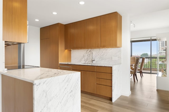 3831 Turtle Creek Blvd Unit 7E, Dallas, TX 75219 - kitchen featuring brown cabinets, light stone countertops, a sink, light wood-style floors, and tasteful backsplash