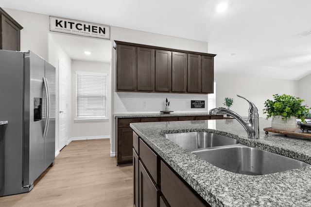 4016 Glastonbury Rd, Mckinney, TX 75071 - kitchen with dark brown cabinets, a sink, stainless steel fridge with ice dispenser, dark stone counters, and light wood-type flooring
