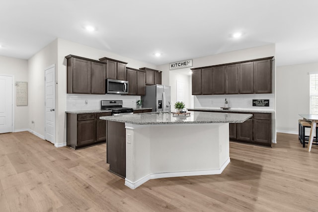 4016 Glastonbury Rd, Mckinney, TX 75071 - kitchen with light wood-style floors, backsplash, stainless steel appliances, and dark brown cabinets