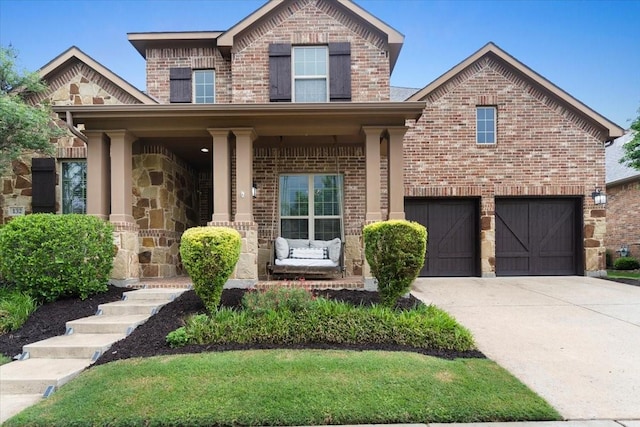 traditional-style house featuring a porch, brick siding, concrete driveway, and a garage