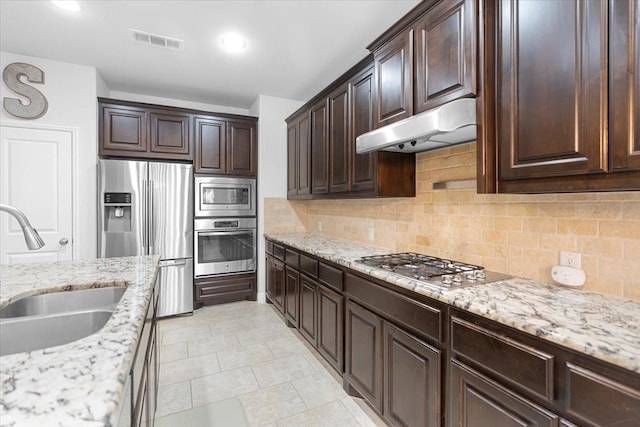 kitchen with dark brown cabinetry, a sink, stainless steel appliances, under cabinet range hood, and visible vents