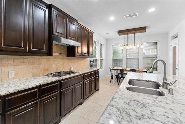 kitchen with decorative backsplash, visible vents, stainless steel gas cooktop, a sink, and under cabinet range hood