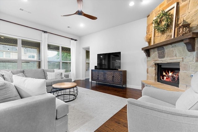 living room featuring a ceiling fan, visible vents, a fireplace, wood finished floors, and baseboards