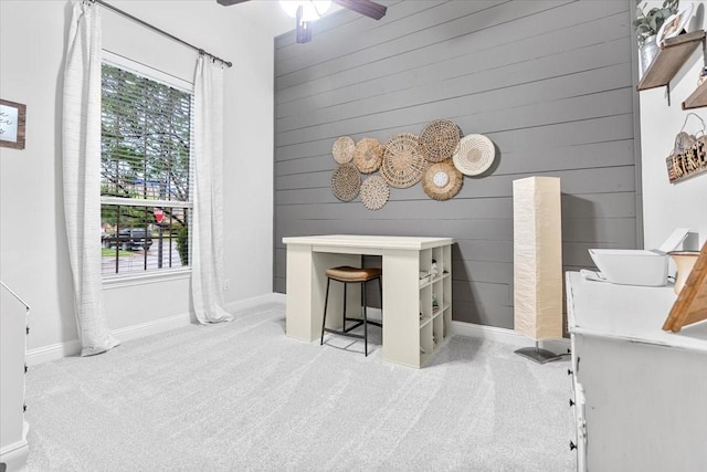 office area with baseboards, carpet flooring, ceiling fan, and wood walls